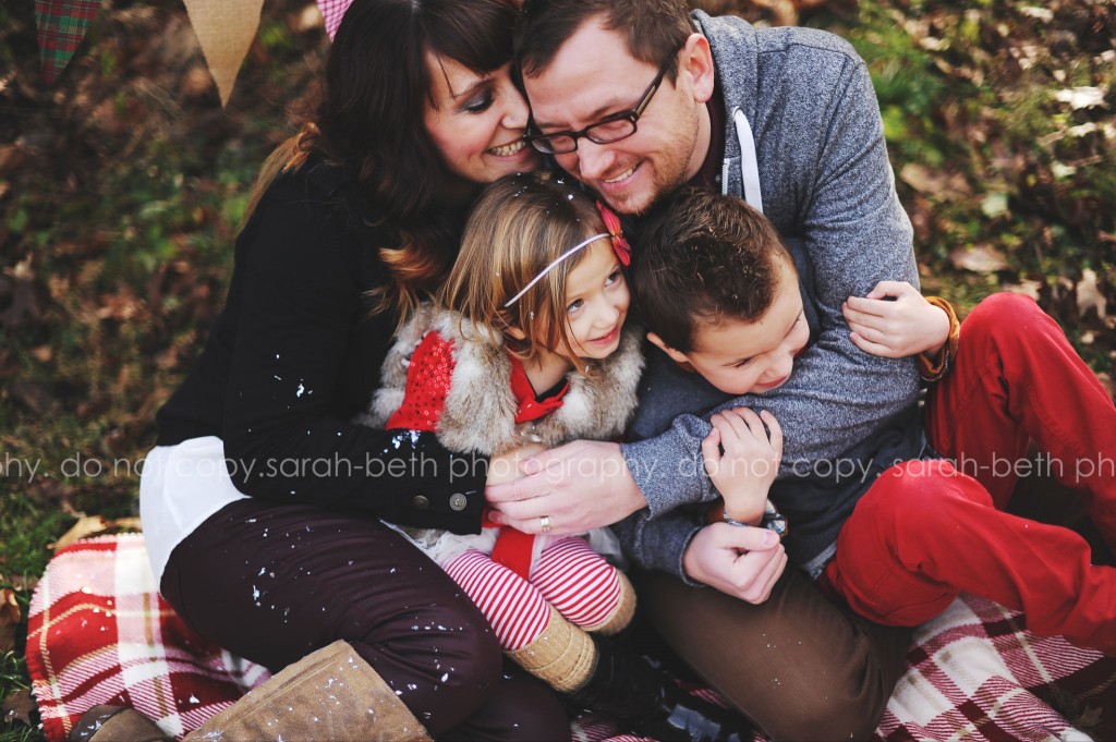 Portrait of family sitting on ground outside by Sarah-Beth Photography