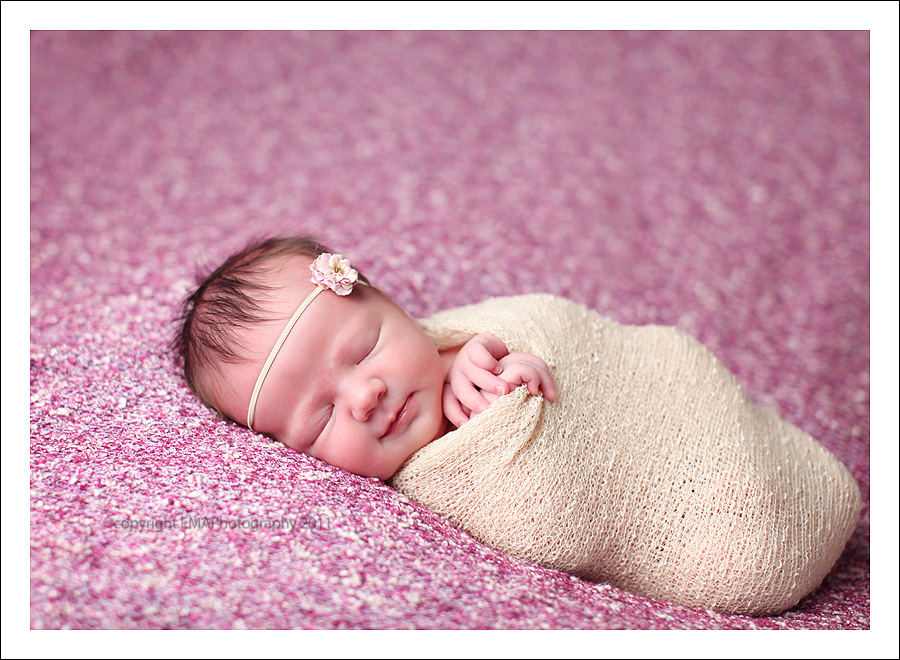Newborn portrait of baby girl on pink background by EMA PHOTOGRAPHY