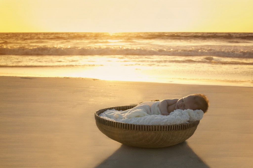 Portrait of newborn in basket on beach by Anja McDonald