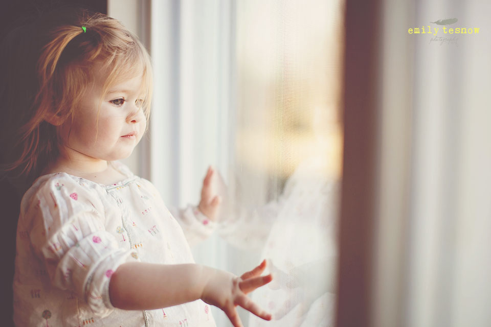 Lifestyle Portrait of young girl looking out window by Emily Tesnow Photography