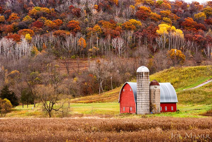 Red barn in colorful autumn valley.