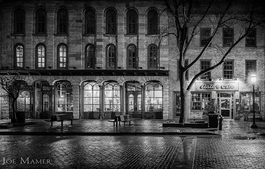 Stone and brick architecture along Saint Anthony Main street in Minneapolis, Minnesota at night after rain shower.